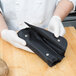 A person in white gloves holding a black bag with the Dexter-Russell 7 Piece Garnishing Tools set.