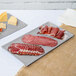 A Tablecraft natural cast aluminum rectangular cooling platter with meat and cheese on it.