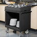 A black Cambro flatware cart with plates and utensils on it.