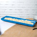 A sky blue rectangular Tablecraft tray with food in it.