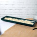 A Tablecraft hunter green rectangular cast aluminum tray with food on a table.