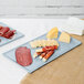 A gray Tablecraft cast aluminum rectangular cooling platter with meat and cheese on it.