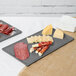 A Tablecraft granite cast aluminum rectangular cooling platter with meat and cheese on it.