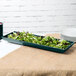 A hunter green cast aluminum rectangular platter with lettuce on it.