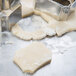 A close-up of Ateco stainless steel plaque cookie cutters cutting dough.