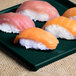 A Tablecraft hunter green with white speckle rectangular cooling platter with sushi on it.