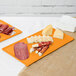 Two orange Tablecraft cast aluminum rectangular cooling platters with food on them.