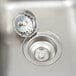 A close-up of a stainless steel drop-in sink with a drain and strainer.