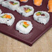 A sushi roll on a maroon speckled Tablecraft cooling platter.