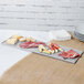 A Tablecraft natural cast aluminum half long rectangular cooling platter with meat and cheese on a table.