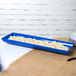 A cobalt blue rectangular tray with food in it.