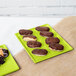 A lime green Tablecraft cast aluminum rectangular cooling platter with chocolate covered donuts and pastries on it.