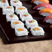 A Tablecraft midnight speckle cast aluminum rectangular cooling platter with sushi rolls on a table.