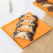 A Tablecraft orange cast aluminum rectangular cooling platter with pastries on it.