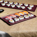 A maroon speckled rectangular Tablecraft metal cooling platter with sushi on a table.