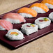 Maroon speckled cast aluminum Tablecraft rectangular cooling platter with sushi on a table.