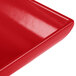 A close up of a red Tablecraft cast aluminum rectangular tray with a shiny surface.