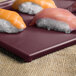 A maroon speckled rectangular Tablecraft cooling platter with sushi on it.