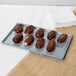 A Tablecraft gray cast aluminum rectangular cooling platter with chocolate covered donuts on a white plate.