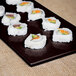 A Tablecraft midnight speckle rectangular cast aluminum platter with sushi rolls on it.