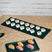 A Tablecraft hunter green and white speckled rectangular cast aluminum cooling platter with sushi on a table.