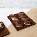 A brown Tablecraft cast aluminum rectangular cooling platter with chocolate covered pastries on it.