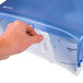 A hand opening a blue and white San Jamar Twin Classic double roll toilet paper dispenser.