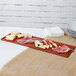 A Tablecraft copper cast aluminum long rectangular cooling platter with meat and cheese on a table.