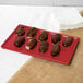 A chocolate covered donut on a red Tablecraft rectangular cooling platter.