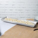 A Tablecraft natural cast aluminum rectangular platter with food on it.
