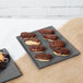 A Tablecraft granite cast aluminum rectangular cooling platter with chocolate covered pastries on a table.