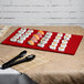 A Tablecraft red cast aluminum rectangular platter with sushi on a table.