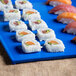 A Tablecraft blue speckle rectangular cast aluminum platter with sushi on it.