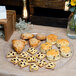 A Fineline clear plastic scalloped catering tray with pastries on it.
