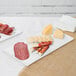 A Tablecraft white cast aluminum rectangular cooling platter with meat and cheese on it.