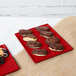 A chocolate covered donut on a red Tablecraft cast aluminum cooling platter.