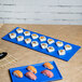 A Tablecraft blue speckle cast aluminum rectangular cooling platter with sushi on a blue surface.