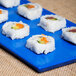 A Tablecraft blue speckle cast aluminum long rectangular cooling platter with sushi rolls on it.