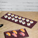 A maroon speckle rectangular cast aluminum tray with sushi on a table.