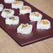 A Tablecraft maroon speckle rectangular cast aluminum cooling platter with sushi on it.