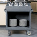 A granite gray Cambro dish cart with plates and silverware on it.