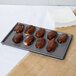 A Tablecraft granite cast aluminum rectangular cooling tray with chocolate covered pastries on a gray surface.
