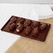 A brown Tablecraft rectangular cast aluminum platter with chocolate covered donuts.