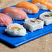 A Tablecraft blue speckled rectangular cast aluminum cooling platter with sushi on a table.