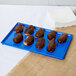 A chocolate covered pastry on a cobalt blue Tablecraft cooling platter.