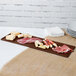A brown Tablecraft cast aluminum rectangular platter with meat and cheese on a table.