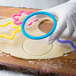A person using a Wilton plastic cookie cutter to make a cookie.