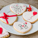 A plate of heart shaped cookies decorated with bows, red hearts, and drawings of people.