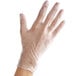 A hand wearing Noble Products clear plastic gloves.