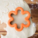 A Wilton flower-shaped cookie cutter on a ball of dough.